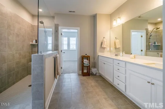 a bathroom with a double vanity sink a large mirror and shower