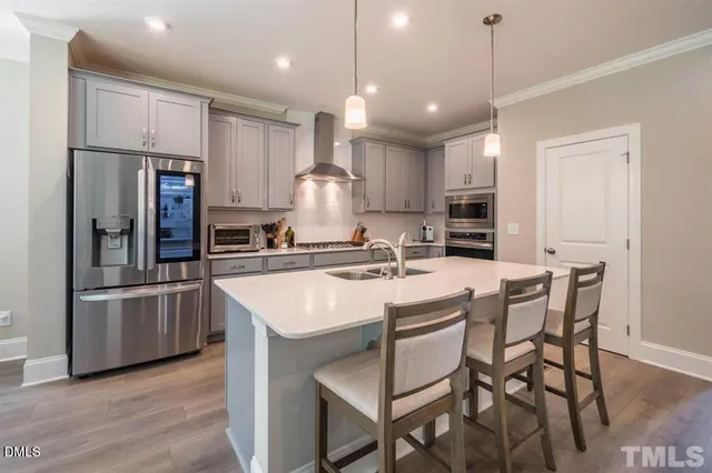 a kitchen with stainless steel appliances granite countertop a sink a stove a refrigerator and island with wooden floor