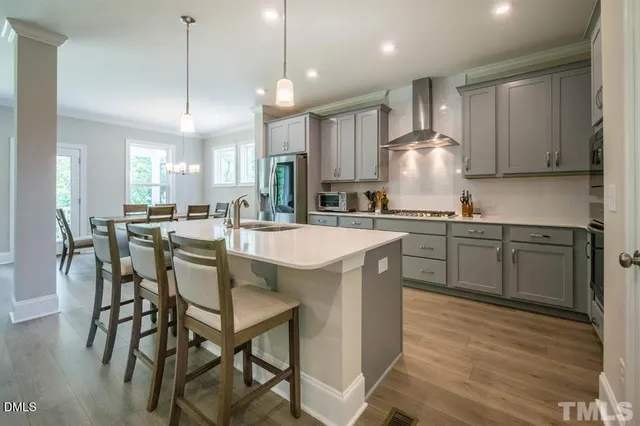 a kitchen with stainless steel appliances a table chairs sink and cabinets