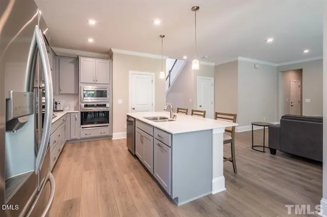 a kitchen with a sink refrigerator and wooden floor
