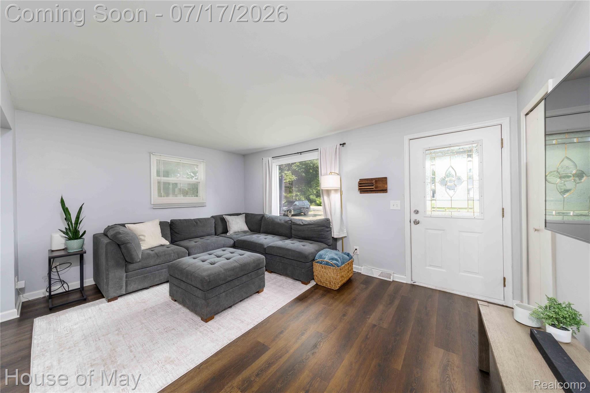 Living area featuring wood-finish flooring, light grey wall paint, and white baseboards