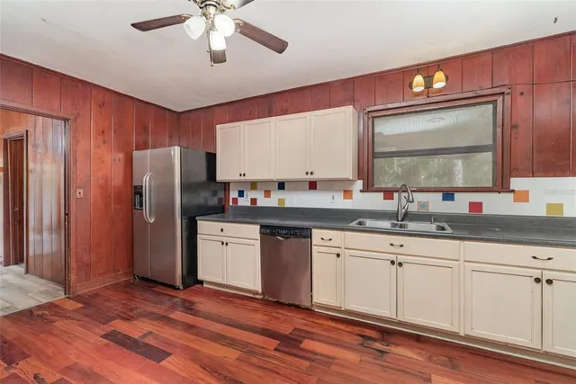 a kitchen with granite countertop a sink cabinets stainless steel appliances and a window