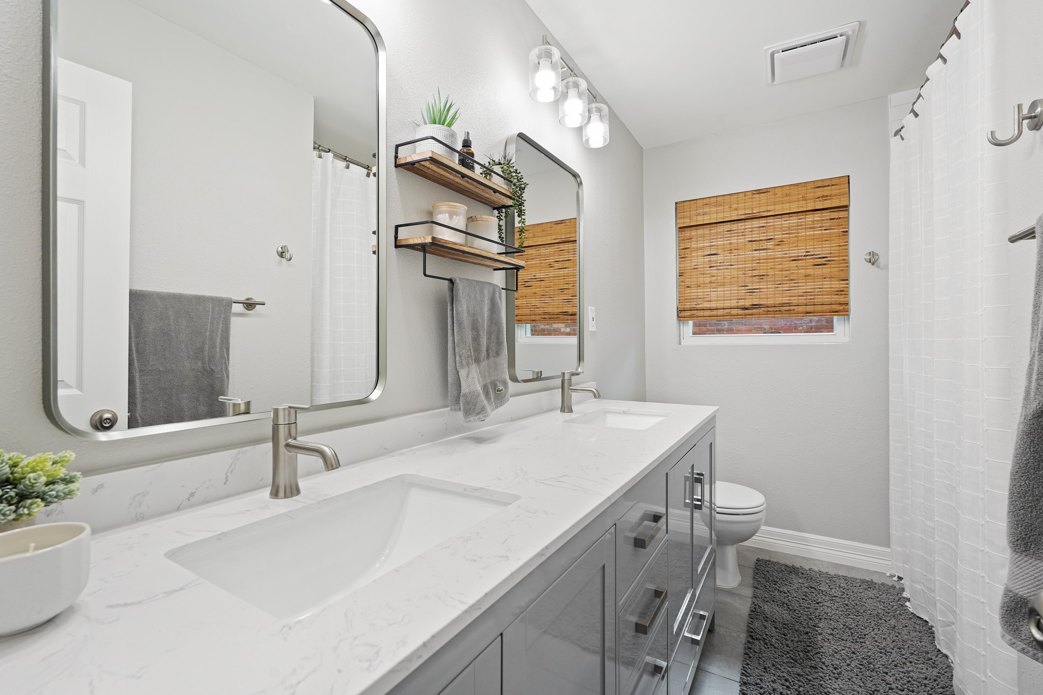 5242 Sanford Road Houston, TX 77035 - Photo 24 of 34 Secondary bathroom has also recently been renovated! Double sink vanity featuring new countertops and sleek fixtures. New tile flooring, large mirrors, modern finishes and new tub and tile surround completed by a stylish open shelving make this a perfect bathroom for guests or family.