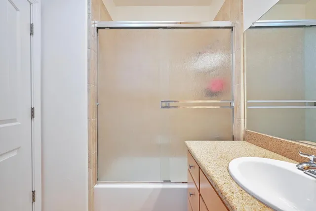 a bathroom with a granite countertop shower and a sink