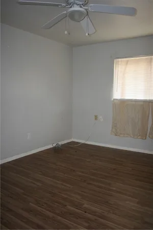 a view of an empty room with wooden floor and a window