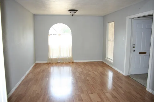 an empty room with wooden floor and window