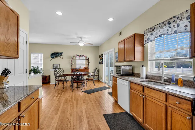 a kitchen with stainless steel appliances granite countertop a refrigerator a sink dishwasher a stove and white countertops with wooden floor