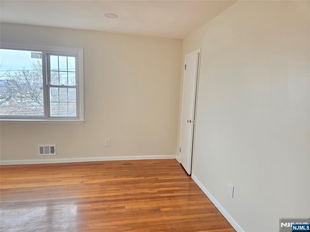413 Farnham Avenue Lodi, NJ 07644 - Photo 3 of 12 an empty room with wooden floor and windows