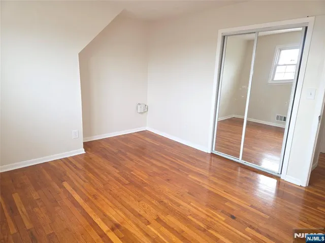 an empty room with wooden floor and mirror