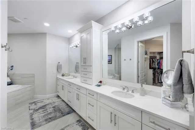a bathroom with a double vanity sink mirror double and bathtub