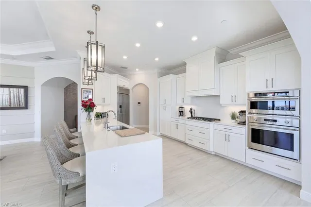 a kitchen with stainless steel appliances kitchen island granite countertop a stove a sink a refrigerator and a refrigerator