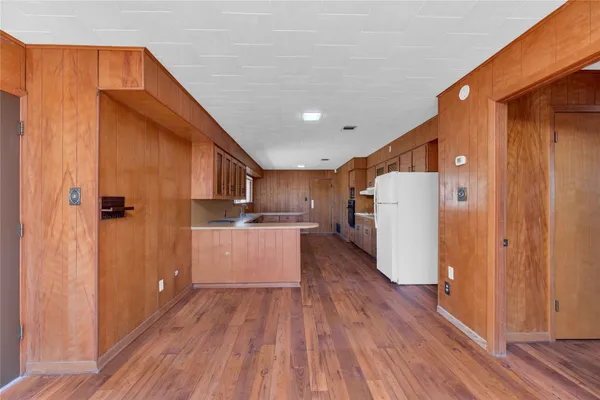 a kitchen with refrigerator and wooden floor