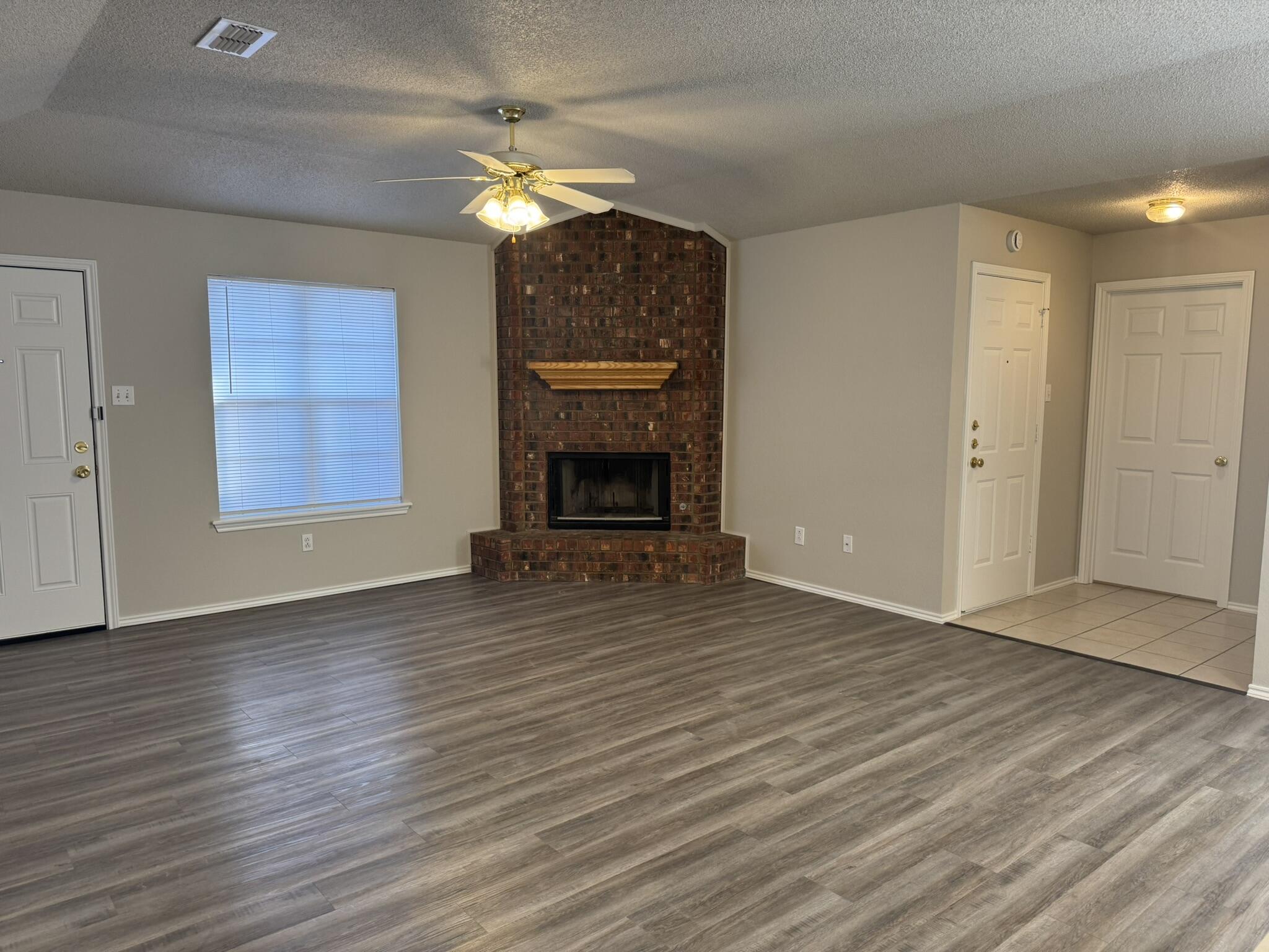 209 Grover Avenue Lubbock, TX 79416 - Photo 3 of 19 a view of an empty room with wooden floor fireplace and a window