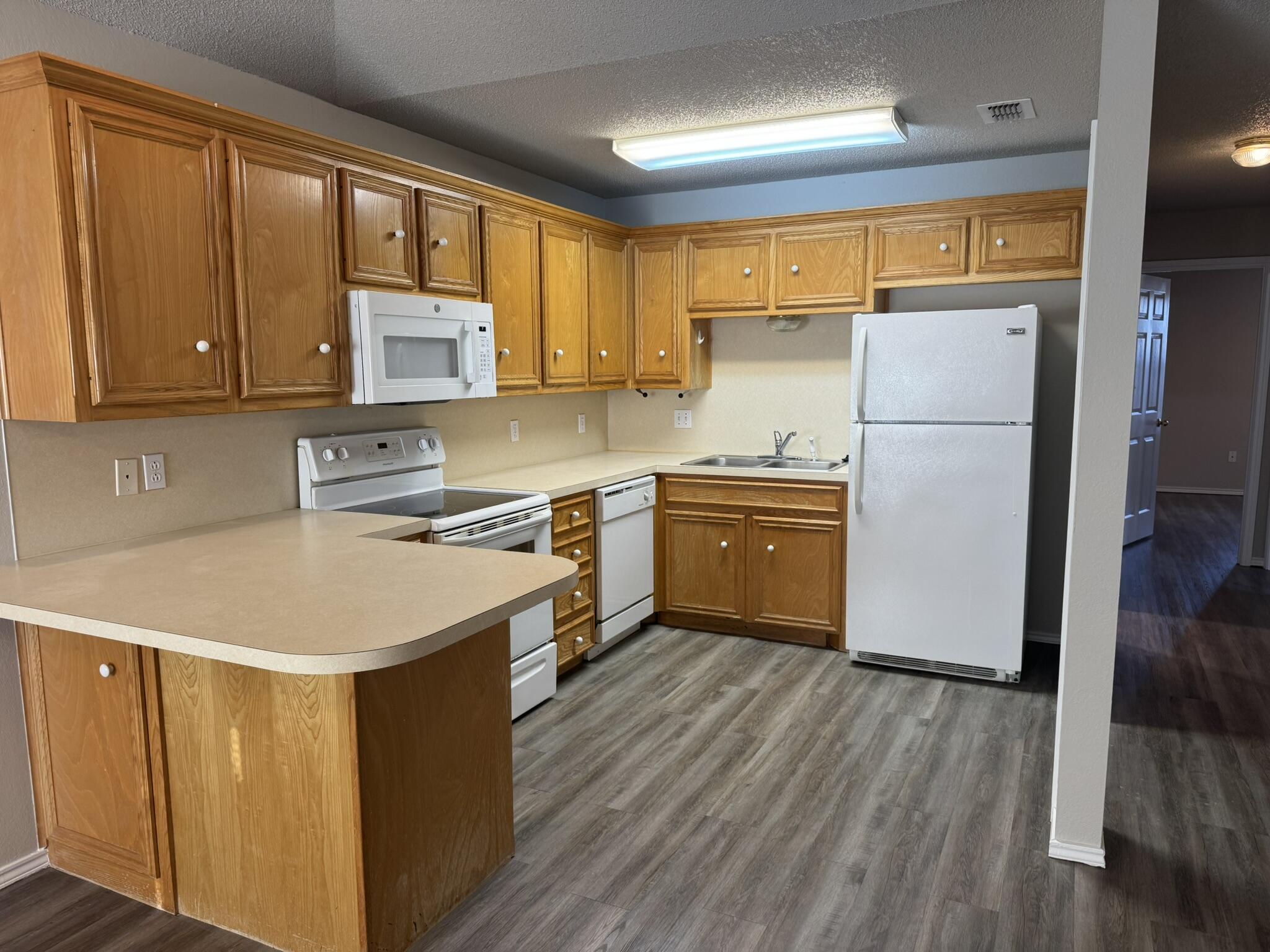 209 Grover Avenue Lubbock, TX 79416 - Photo 6 of 19 a kitchen with a refrigerator a sink and wooden cabinets