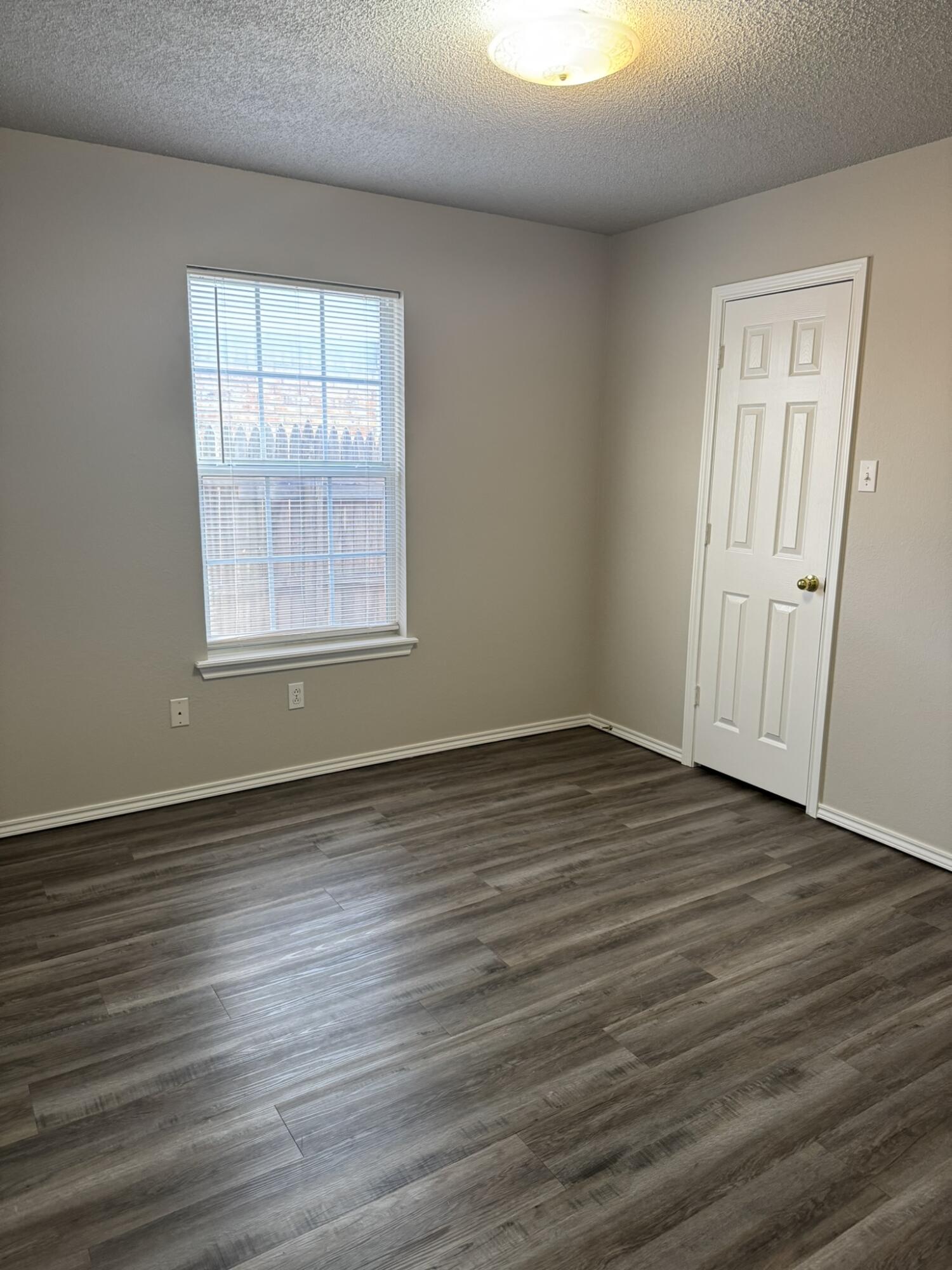209 Grover Avenue Lubbock, TX 79416 - Photo 9 of 19 an empty room with wooden floor and windows