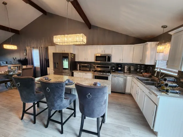 a kitchen with stainless steel appliances kitchen island granite countertop a sink a stove a table and chairs