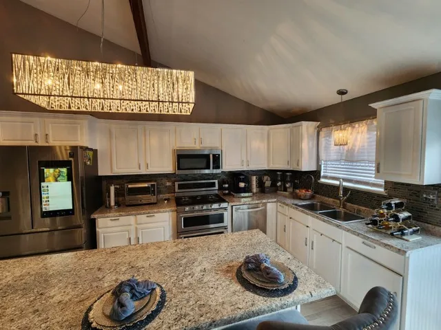 a kitchen with stainless steel appliances kitchen island granite countertop a sink and stove