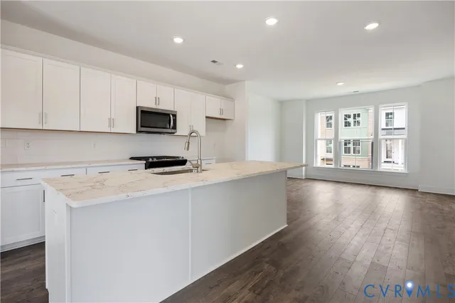 a kitchen with stainless steel appliances granite countertop a stove a sink and a refrigerator