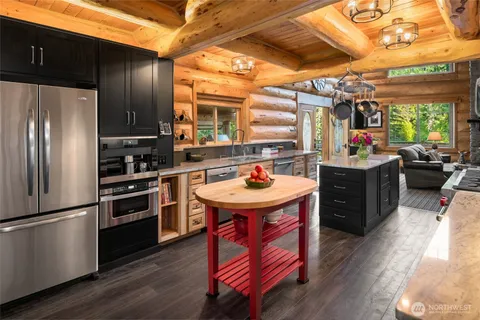 a kitchen with stainless steel appliances kitchen island granite countertop a table chairs and a refrigerator