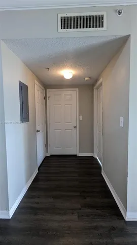 a view of a hallway with wooden floor and a cabinet