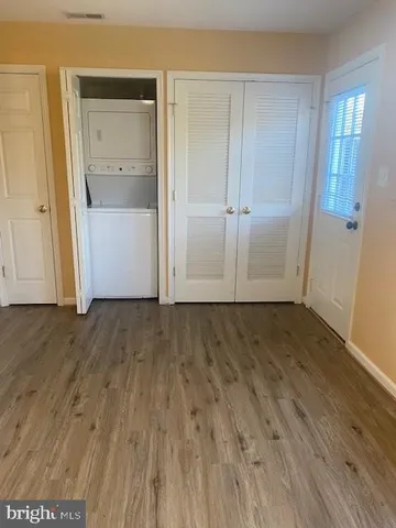 an empty room with wooden floor & closet area