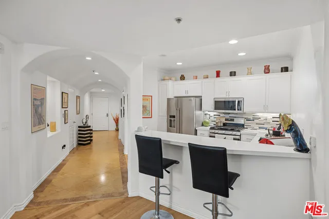 a kitchen with stainless steel appliances a stove a refrigerator white cabinets a dining table and chairs