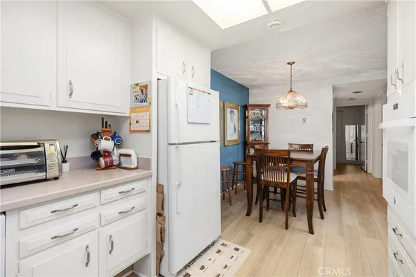 a kitchen with granite countertop a refrigerator a stove a dining table and chairs with wooden floor