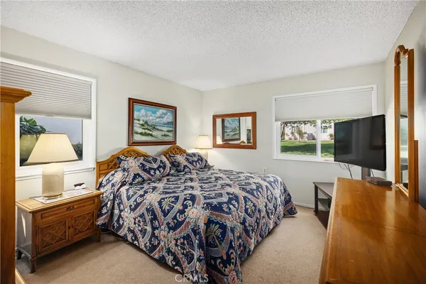 a bedroom with a large bed and a flat tv screen on dresser