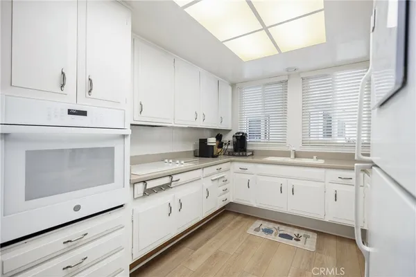 a kitchen with granite countertop white cabinets and white appliances
