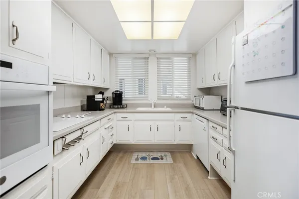 a kitchen with granite countertop white cabinets and white appliances