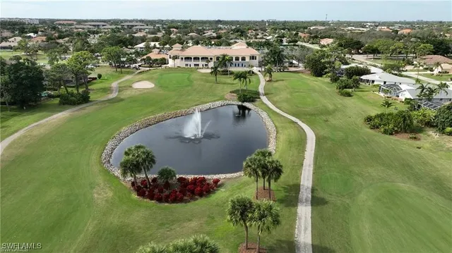 a view of a park that has a sign board large trees