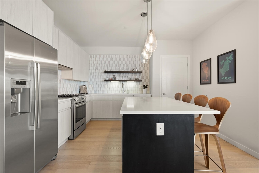45 West 3rd Street, Unit 512 Boston, MA 02127 - Photo 17 of 40 a kitchen with stainless steel appliances granite countertop a sink a stove a refrigerator with white cabinets and wooden floor