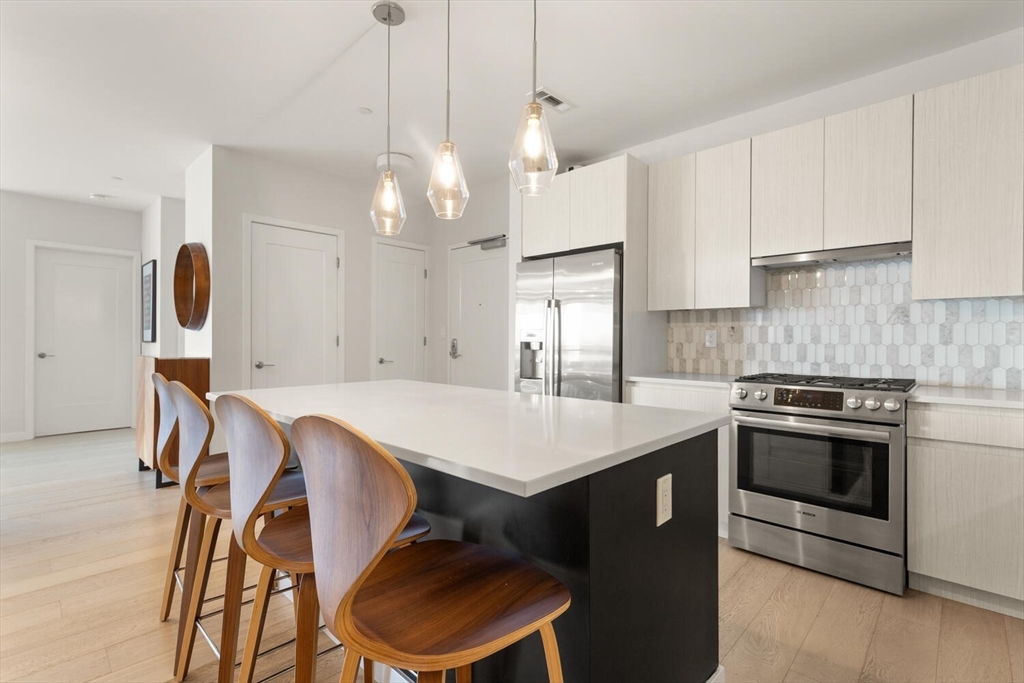 45 West 3rd Street, Unit 512 Boston, MA 02127 - Photo 18 of 40 a kitchen that has a sink a stove and a table with chairs in it