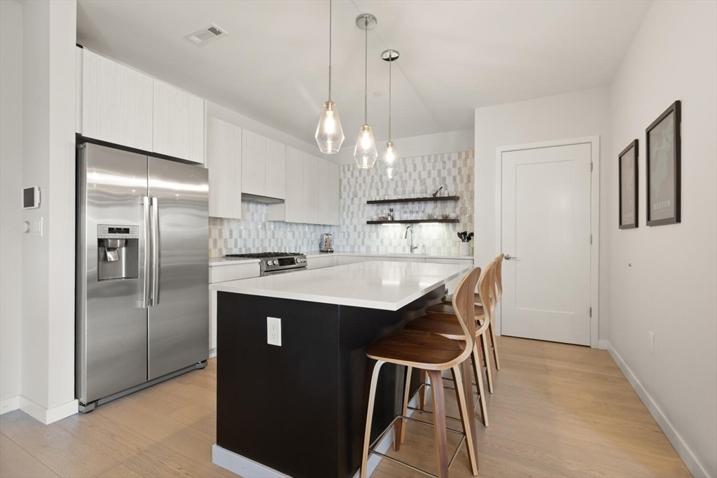 45 West 3rd Street, Unit 512 Boston, MA 02127 - Photo 19 of 40 a kitchen with kitchen island a dining table chairs stainless steel appliances and cabinets