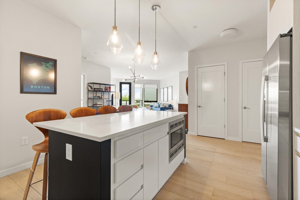 45 West 3rd Street, Unit 512 Boston, MA 02127 - Photo 20 of 40 a kitchen with a sink a counter top space stainless steel appliances and a chandelier