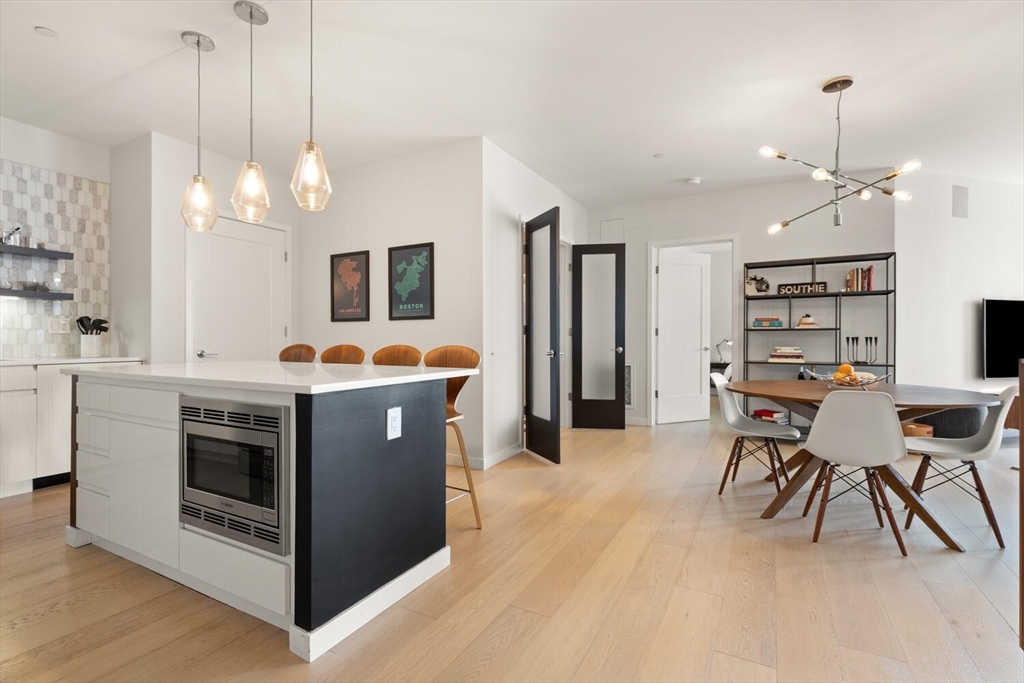 45 West 3rd Street, Unit 512 Boston, MA 02127 - Photo 8 of 40 a kitchen with stainless steel appliances granite countertop a stove a sink a refrigerator a dining table and chairs with wooden floor