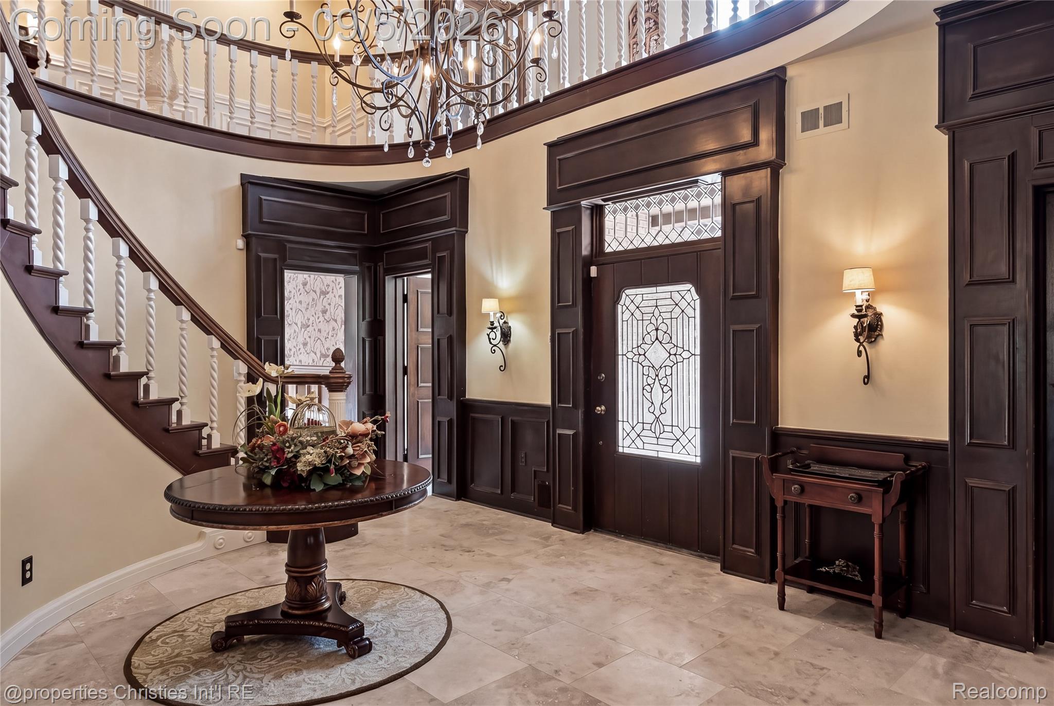 1540 Mill Race Road Rochester, MI 48306 - Photo 13 of 99 Two-story foyer featuring a curved staircase with ornate balusters, dark wood wainscoting, and a decorative tile floor