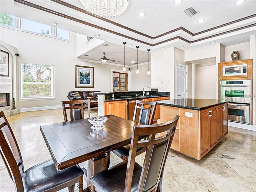 13161 Lake Butler Boulevard Windermere, FL 34786 - Photo 11 of 30 a kitchen with stainless steel appliances granite countertop a stove a refrigerator a dining table and chairs with wooden floor