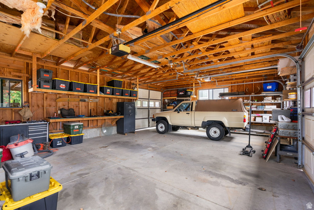 615 East Maple Street Mapleton, UT 84664 - Photo 24 of 30 Spacious garage featuring concrete flooring, exposed wood beam ceiling, two overhead garage doors, built-in shelving, and a workbench area