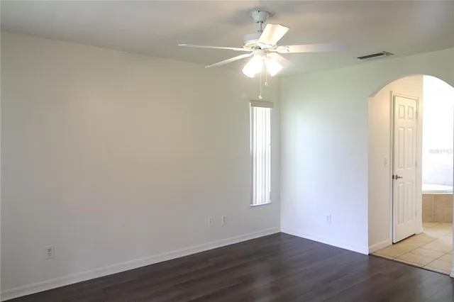 an empty room with wooden floor fan and window