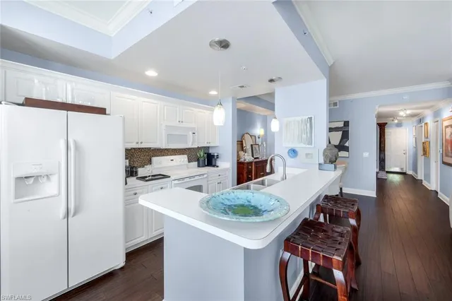 a kitchen with stainless steel appliances kitchen island a table chairs and a refrigerator