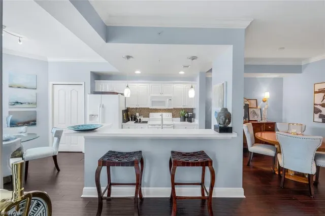 a kitchen with stainless steel appliances kitchen island granite countertop a dining table chairs and a refrigerator