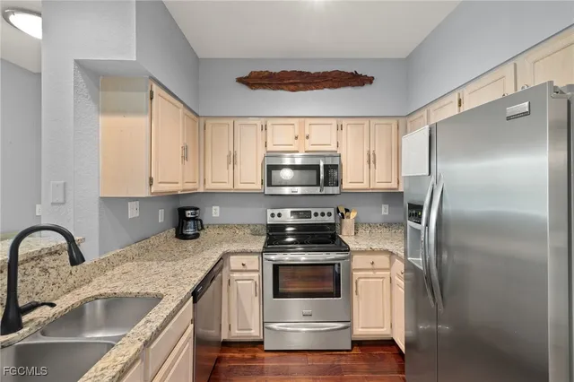 a kitchen with kitchen island granite countertop a stove a sink and refrigerator