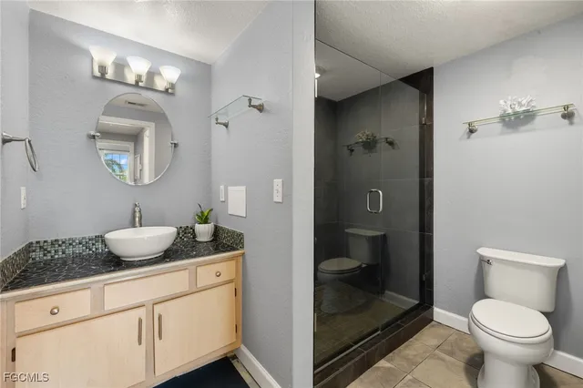 a bathroom with a granite countertop sink a toilet and shower