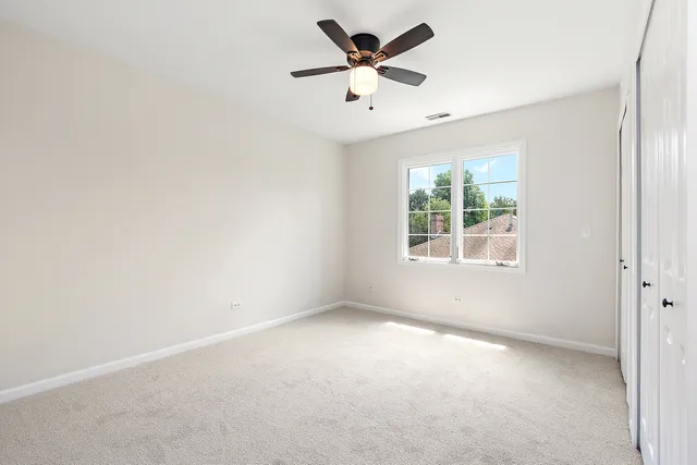 an empty room with a window and a fan