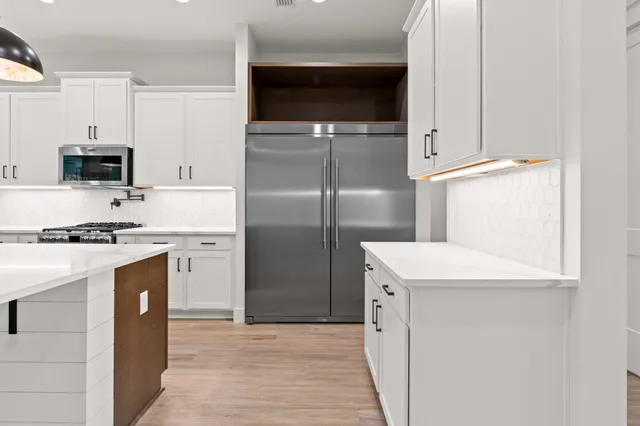 an empty room with wooden floor chandelier fan and windows