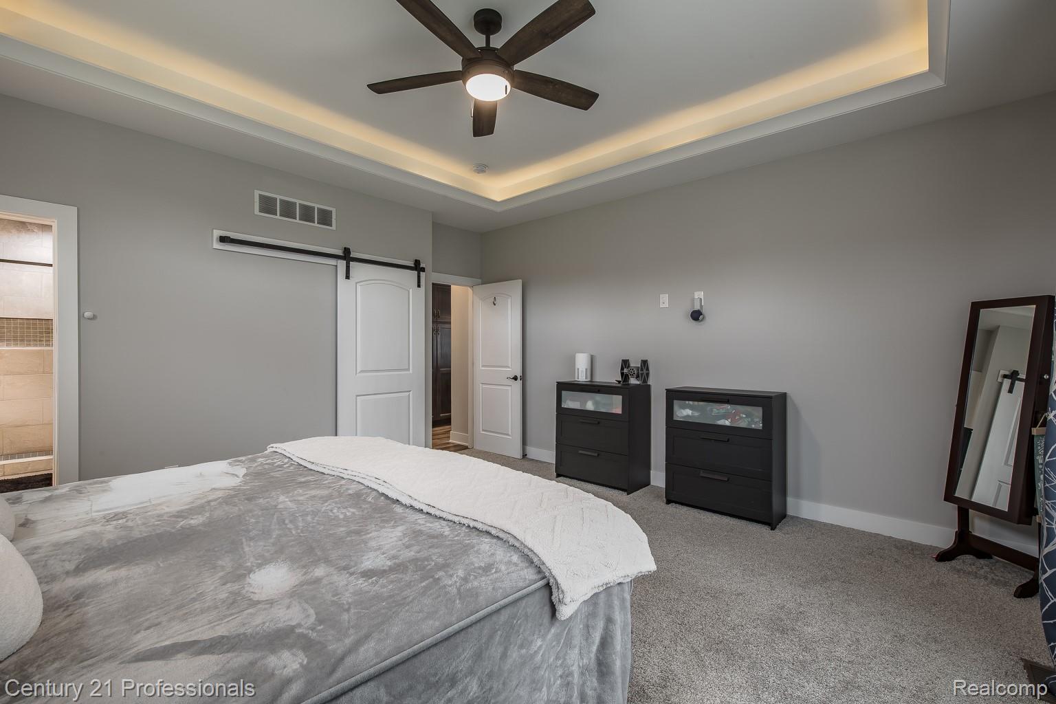 4914 TORATOLA Lane Howell, MI 48843 - Photo 22 of 39 Bedroom with a barn door, carpet, ceiling fan, and a raised ceiling