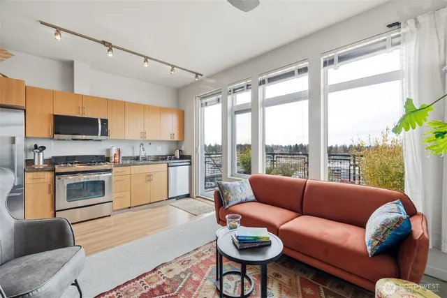 a living room with furniture a fireplace kitchen view and a large window