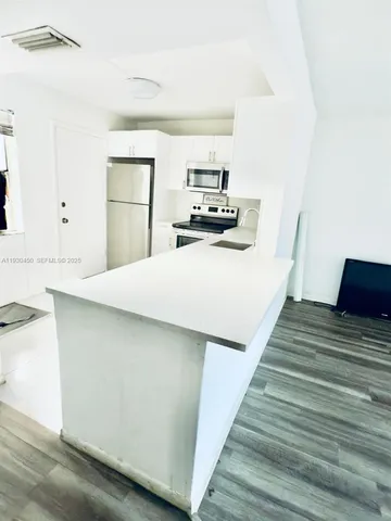 a kitchen with kitchen island a stove a refrigerator and a sink