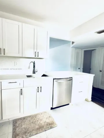 a kitchen with a sink a stove and white cabinets
